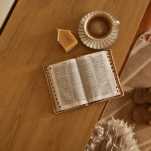 Cozy morning scene with open book, coffee, and candle on a wooden table