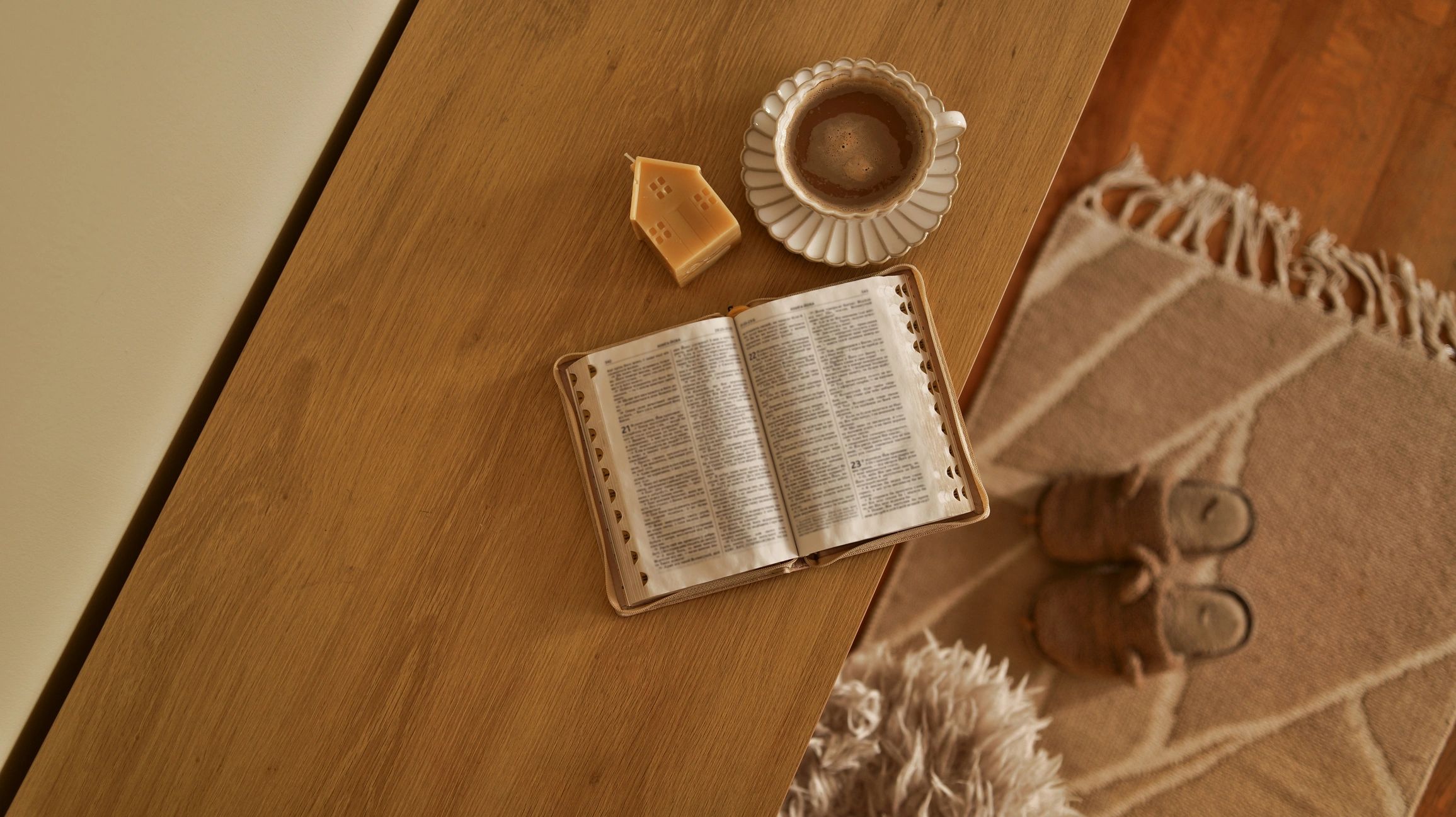 Cozy morning scene with open book, coffee, and candle on a wooden table